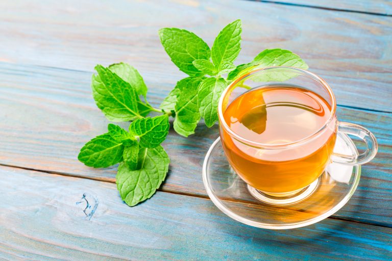 A cup of mint tea on blue wood textured background